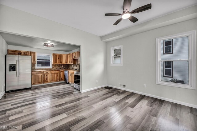 397 Furnace Rd, Conneaut, OH 44030 - kitchen with appliances with stainless steel finishes, wood finished floors, a ceiling fan, brown cabinets, and tasteful backsplash