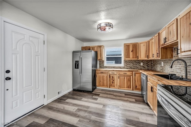 397 Furnace Rd, Conneaut, OH 44030 - kitchen featuring appliances with stainless steel finishes, butcher block counters, decorative backsplash, light wood finished floors, and a textured ceiling