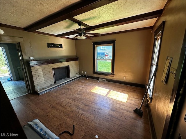 872 Keeney St, Akron, OH 44310 - unfurnished living room featuring wood finished floors, a textured ceiling, a fireplace, beamed ceiling, and a ceiling fan