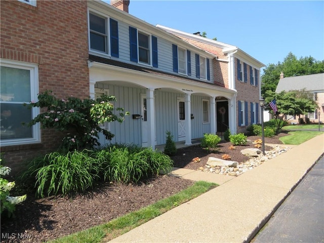 1609 S Main St Unit 22C, North Canton, OH 44709 - view of front facade with covered porch, brick siding, board and batten siding, and a chimney