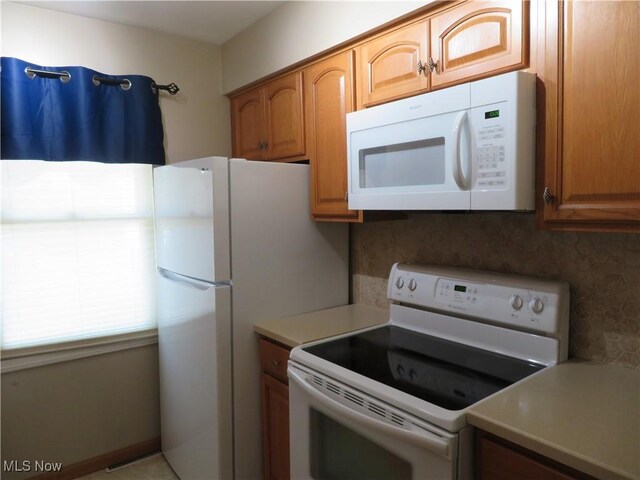 1609 S Main St Unit 22C, North Canton, OH 44709 - kitchen with white appliances, light countertops, tasteful backsplash, and brown cabinetry