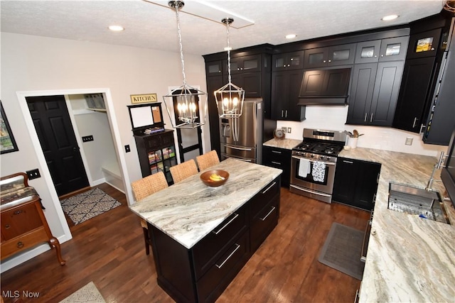 8025 Wadsworth Rd, Wadsworth, OH 44281 - kitchen featuring appliances with stainless steel finishes, dark wood-type flooring, a center island, light stone counters, and hanging light fixtures