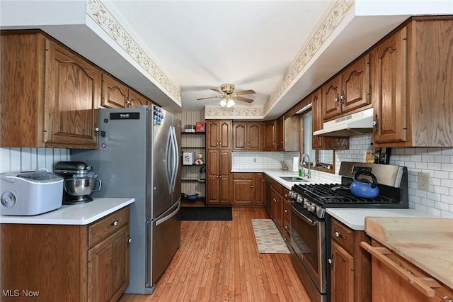 6111 State Route 82, Hiram, OH 44234 - kitchen featuring appliances with stainless steel finishes, under cabinet range hood, ceiling fan, light wood-style floors, and tasteful backsplash