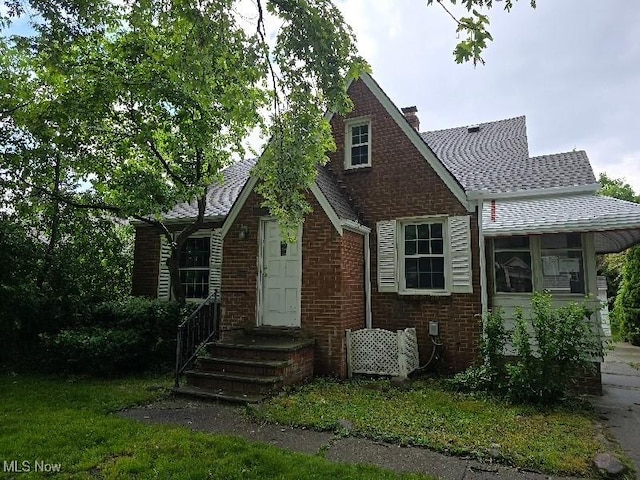 10713 Penfield Ave, Garfield Heights, OH 44125 - view of front of home with a chimney, brick siding, and a shingled roof