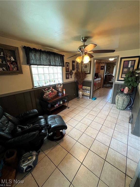 629 Willard Ave SE, Warren, OH 44483 - living area featuring light tile patterned floors, a wainscoted wall, and ceiling fan