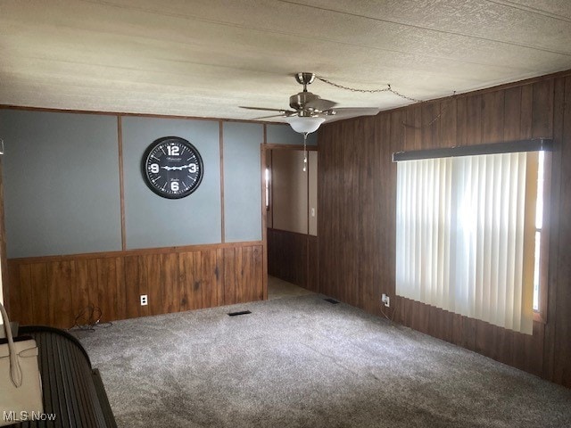 129 Bennett, Vienna, OH 44473 - unfurnished room with ceiling fan, wood walls, carpet, and a wainscoted wall