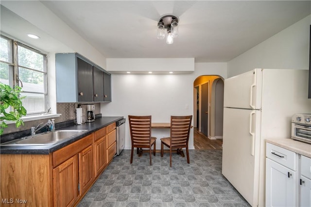 1432 Maxwell Ave NW, Warren, OH 44485 - kitchen featuring arched walkways, freestanding refrigerator, backsplash, dishwasher, and dark countertops