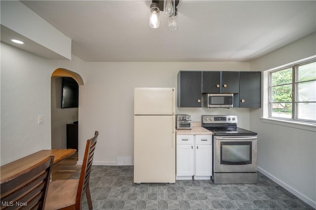 1432 Maxwell Ave NW, Warren, OH 44485 - kitchen featuring stainless steel appliances, arched walkways, light countertops, and white cabinetry