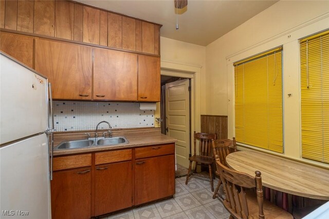 11604 Thornwood Ave, Cleveland, OH 44108 - kitchen featuring freestanding refrigerator, tasteful backsplash, light flooring, and brown cabinets