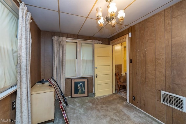 11604 Thornwood Ave, Cleveland, OH 44108 - spare room featuring carpet, wood walls, and a chandelier