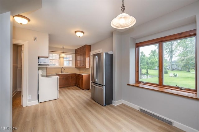 36 Rosedale Blvd, Norwalk, OH 44857 - kitchen with freestanding refrigerator, brown cabinets, range, light wood-style floors, and decorative light fixtures