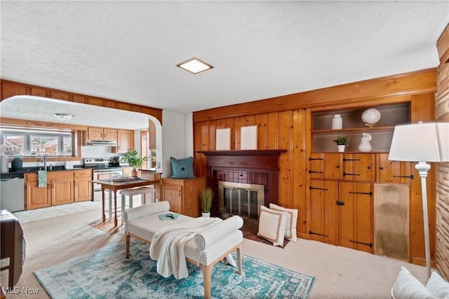 3568 Peninsula Dr, Coventry, OH 44319 - dining space featuring wood walls, light carpet, arched walkways, a textured ceiling, and a brick fireplace