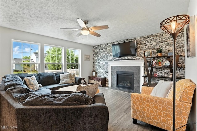 3990 Abigail Dr, Lorain, OH 44053 - living room featuring ceiling fan, wood finished floors, a textured ceiling, and a tile fireplace