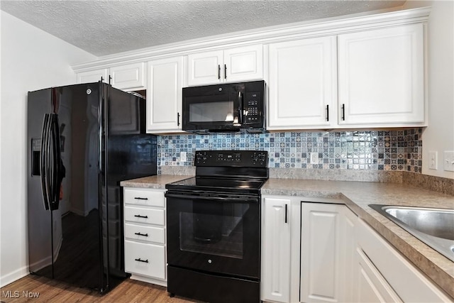 3990 Abigail Dr, Lorain, OH 44053 - kitchen featuring black appliances, light wood-style flooring, white cabinetry, and a textured ceiling