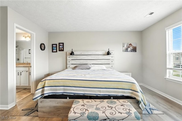 3990 Abigail Dr, Lorain, OH 44053 - bedroom featuring light wood-style flooring, ensuite bathroom, and a textured ceiling