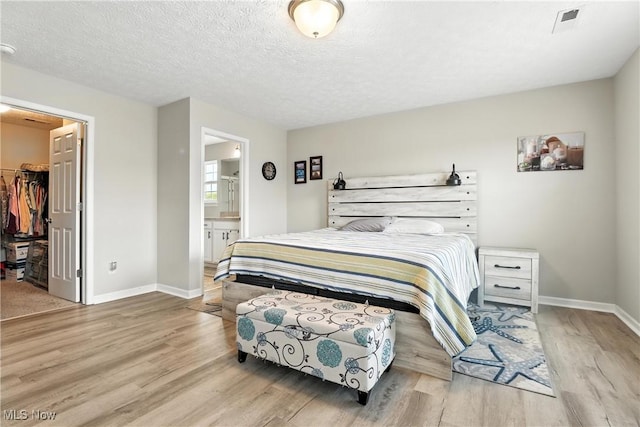 3990 Abigail Dr, Lorain, OH 44053 - bedroom with wood finished floors, a spacious closet, a closet, a textured ceiling, and ensuite bath