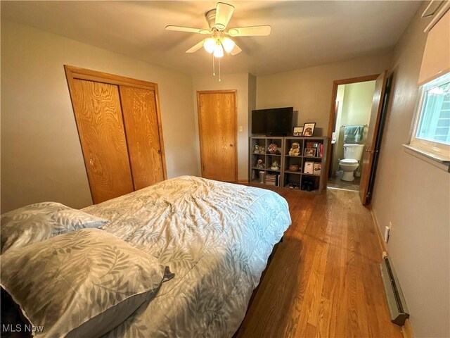 344 17th St NW, Barberton, OH 44203 - bedroom featuring wood finished floors, a baseboard radiator, a closet, ensuite bath, and ceiling fan