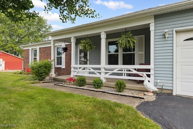 1114 Beechwood Rd, Salem, OH 44460 - view of exterior entry with a porch, brick siding, a yard, and an attached garage