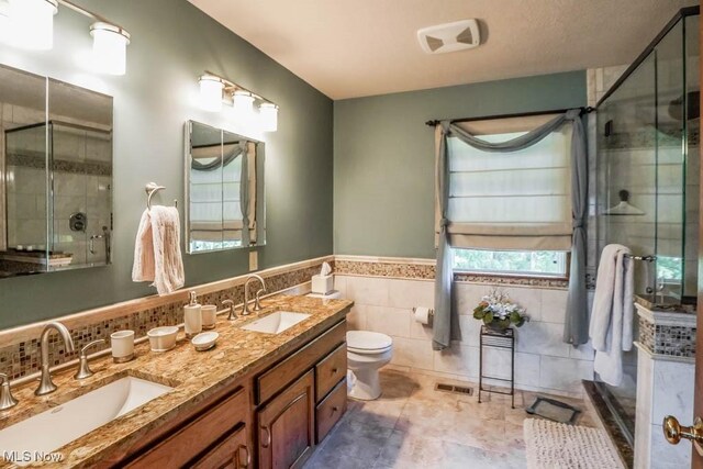 3020 Crookston Ln, Clinton, OH 44216 - full bath with tile walls, a shower stall, double vanity, a wainscoted wall, and tile patterned floors
