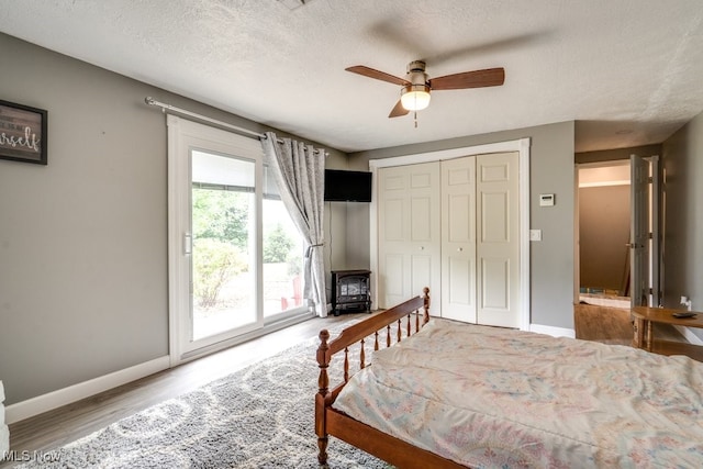 1260 Pleasant Ridge St SE, Minerva, OH 44657 - bedroom featuring a wood stove, wood finished floors, access to exterior, a closet, and a textured ceiling
