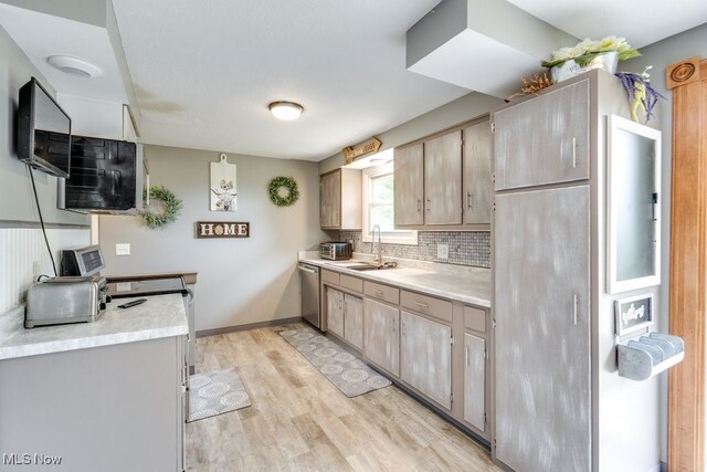 1260 Pleasant Ridge St SE, Minerva, OH 44657 - kitchen featuring stainless steel dishwasher, light wood-type flooring, light countertops, tasteful backsplash, and light brown cabinetry