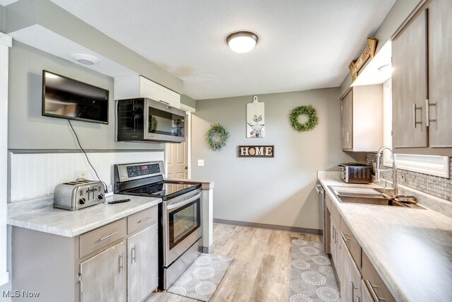 1260 Pleasant Ridge St SE, Minerva, OH 44657 - kitchen with appliances with stainless steel finishes, light countertops, backsplash, and light wood finished floors