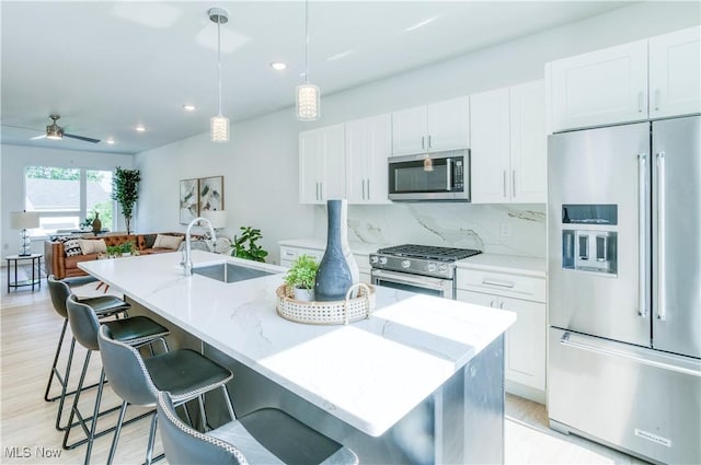 1369 W 74th St, Cleveland, OH 44102 - kitchen featuring stainless steel appliances, white cabinetry, a center island with sink, light stone counters, and recessed lighting