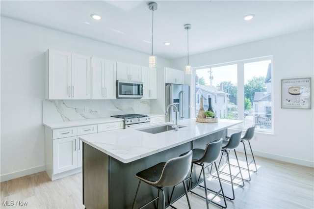 1369 W 74th St, Cleveland, OH 44102 - kitchen with stainless steel appliances, a center island with sink, a breakfast bar area, white cabinets, and tasteful backsplash