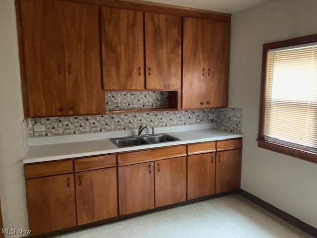 1543 Genesee Rd, South Euclid, OH 44121 - kitchen featuring light countertops, decorative backsplash, and brown cabinets