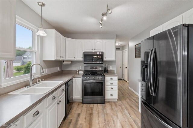7287 Fayette Blvd, Chippewa Lake, OH 44215 - kitchen featuring stainless steel appliances, white cabinetry, light wood-type flooring, hanging light fixtures, and light countertops