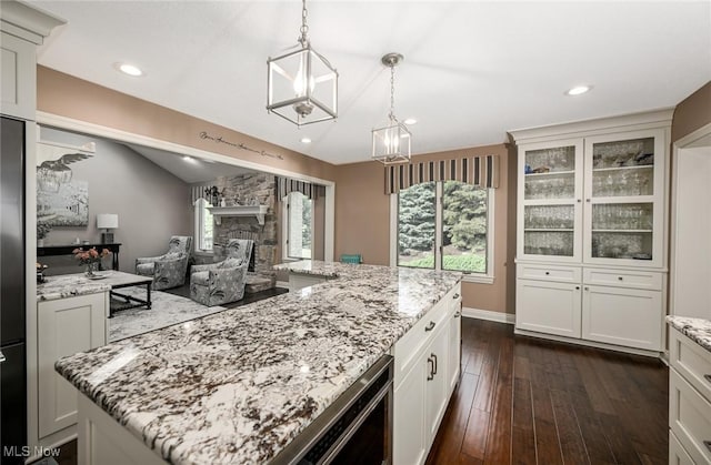 5277 Foxchase Ave NW, Canton, OH 44718 - kitchen with light stone countertops, dark wood-style flooring, a center island, glass insert cabinets, and decorative light fixtures