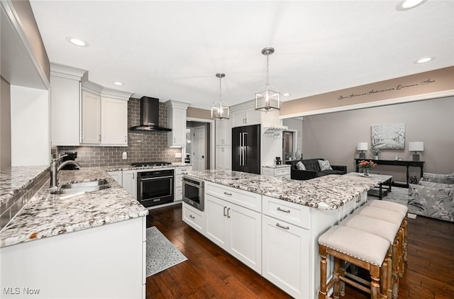 5277 Foxchase Ave NW, Canton, OH 44718 - kitchen with wall chimney exhaust hood, black appliances, a kitchen island, tasteful backsplash, and dark wood-style floors