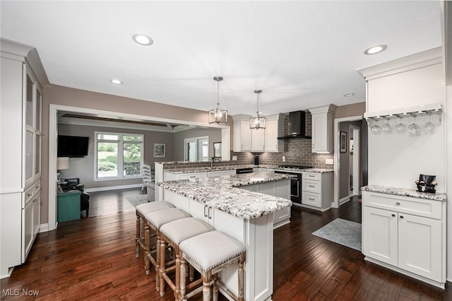 5277 Foxchase Ave NW, Canton, OH 44718 - kitchen with wall chimney range hood, gas range oven, a peninsula, decorative backsplash, and a breakfast bar