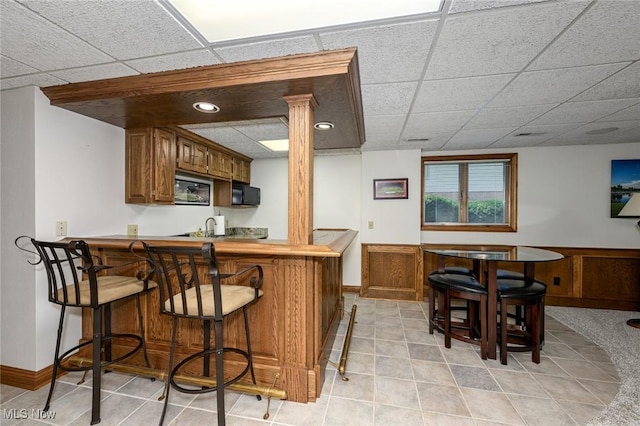 5277 Foxchase Ave NW, Canton, OH 44718 - kitchen featuring black microwave, stainless steel microwave, light tile patterned floors, and a paneled ceiling