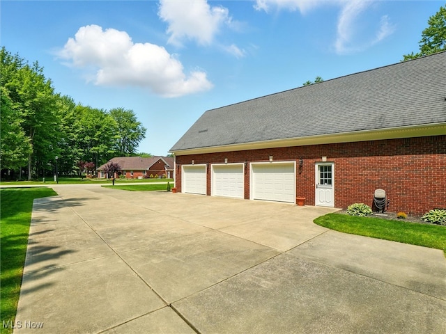 4440 Rutledge Ave, Ashtabula, OH 44004 - view of side of property with a garage, brick siding, driveway, and roof with shingles