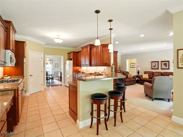 4440 Rutledge Ave, Ashtabula, OH 44004 - kitchen featuring a kitchen bar, white appliances, light tile patterned floors, open floor plan, and decorative light fixtures