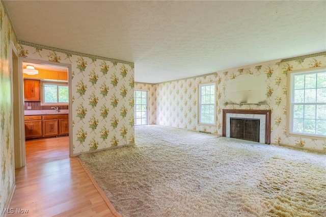34112 Chagrin Blvd Unit 7106, Moreland Hills, OH 44022 - unfurnished living room featuring wallpapered walls, light wood-style flooring, a high end fireplace, and a textured ceiling