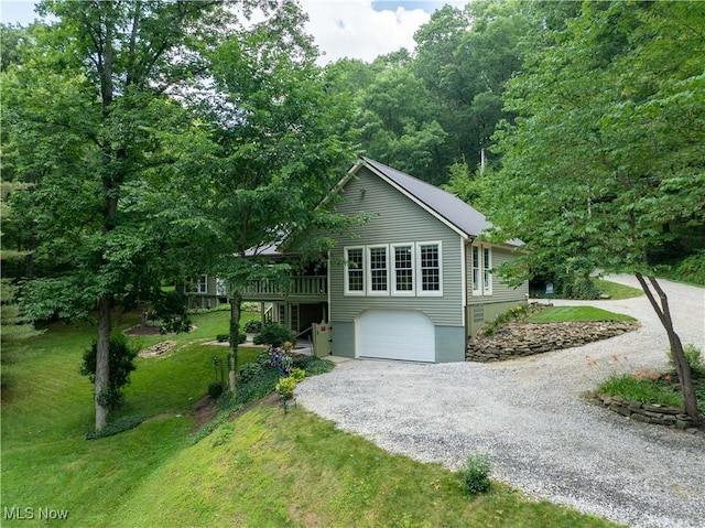 2461 Trailwood Dr SW, Carrollton, OH 44615 - view of front facade featuring gravel driveway, a front lawn, a deck, an attached garage, and a forest view