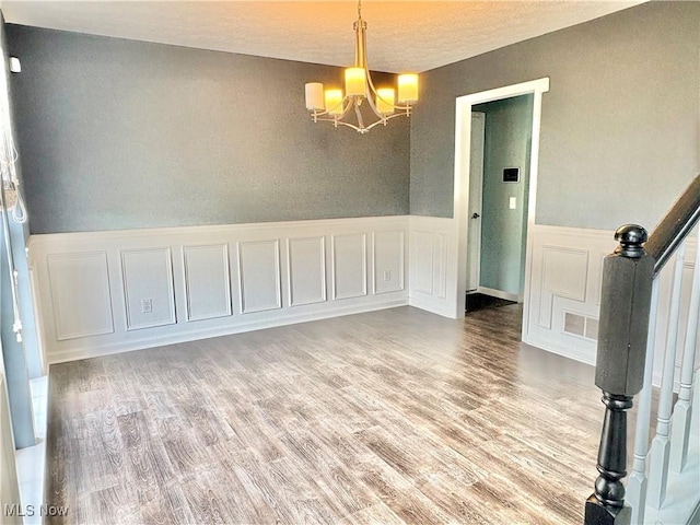 11208 Glen Abbey Dr, North Royalton, OH 44133 - unfurnished room featuring a chandelier, wood finished floors, wainscoting, a decorative wall, and a textured ceiling