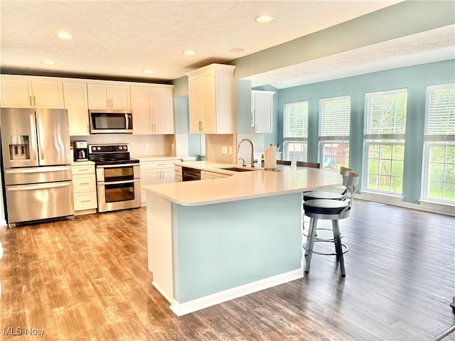 11208 Glen Abbey Dr, North Royalton, OH 44133 - kitchen with appliances with stainless steel finishes, light wood-style flooring, light countertops, a peninsula, and backsplash