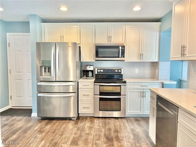 11208 Glen Abbey Dr, North Royalton, OH 44133 - kitchen featuring appliances with stainless steel finishes, light countertops, light wood-style floors, white cabinets, and recessed lighting