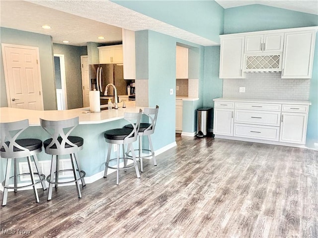 11208 Glen Abbey Dr, North Royalton, OH 44133 - kitchen featuring stainless steel refrigerator with ice dispenser, light wood-style floors, backsplash, a breakfast bar, and vaulted ceiling