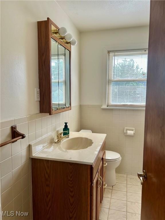 145 Marcia Dr, Austintown, OH 44515 - half bathroom featuring vanity, plenty of natural light, tile walls, and a wainscoted wall