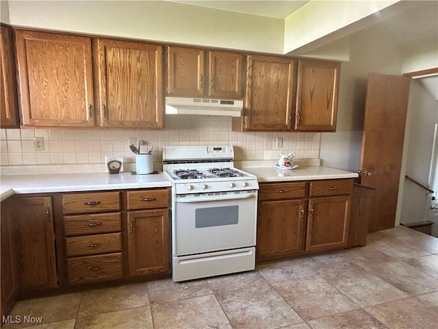 145 Marcia Dr, Austintown, OH 44515 - kitchen with white gas stove, under cabinet range hood, brown cabinets, tasteful backsplash, and light countertops