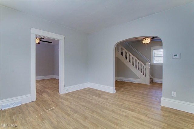 1213 Mckinley Ave, Akron, OH 44306 - spare room with arched walkways, ceiling fan, light wood finished floors, and stairway