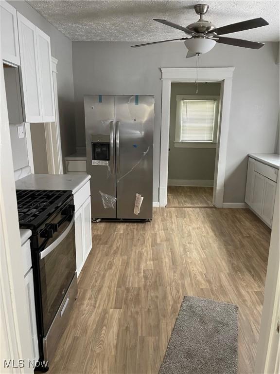 1213 Mckinley Ave, Akron, OH 44306 - kitchen with appliances with stainless steel finishes, a textured ceiling, ceiling fan, light wood-style floors, and white cabinets