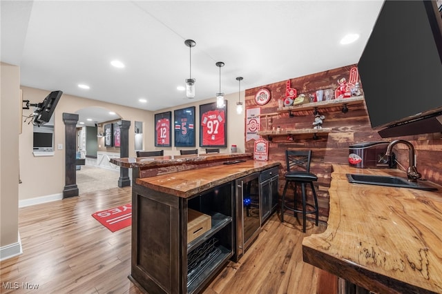 2940 Londonbury St NW, Uniontown, OH 44685 - indoor bar with beverage cooler, arched walkways, wood finished floors, decorative columns, and hanging light fixtures