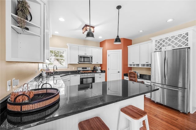 2940 Londonbury St NW, Uniontown, OH 44685 - kitchen with stainless steel appliances, a peninsula, white cabinetry, a breakfast bar, and pendant lighting