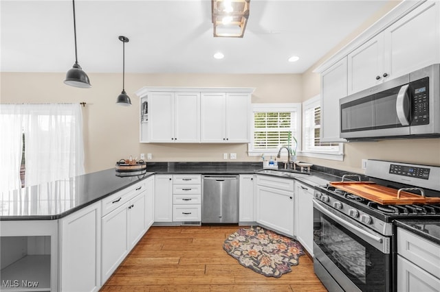 2940 Londonbury St NW, Uniontown, OH 44685 - kitchen featuring stainless steel appliances, light wood finished floors, a peninsula, dark countertops, and white cabinets