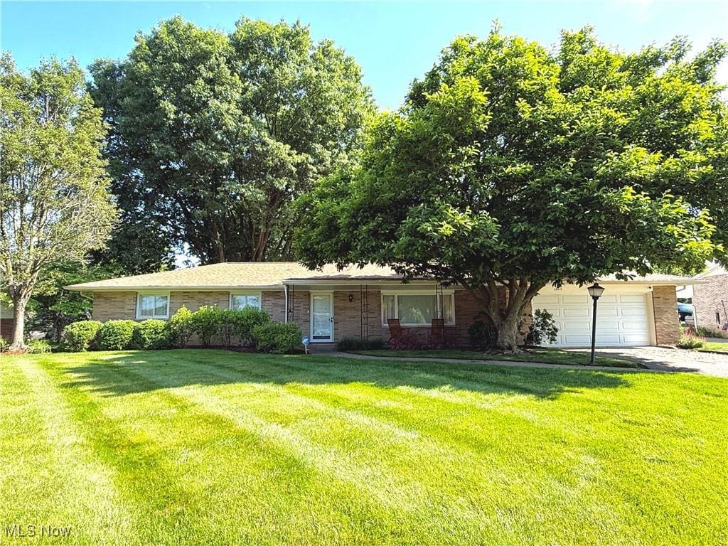 2645 Gladiola St NE, Canton, OH 44705 - view of front of house featuring a front lawn, an attached garage, driveway, and brick siding